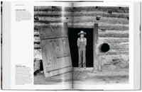 Open book showing a black and white photograph of a boy in overalls standing in a log cabin.