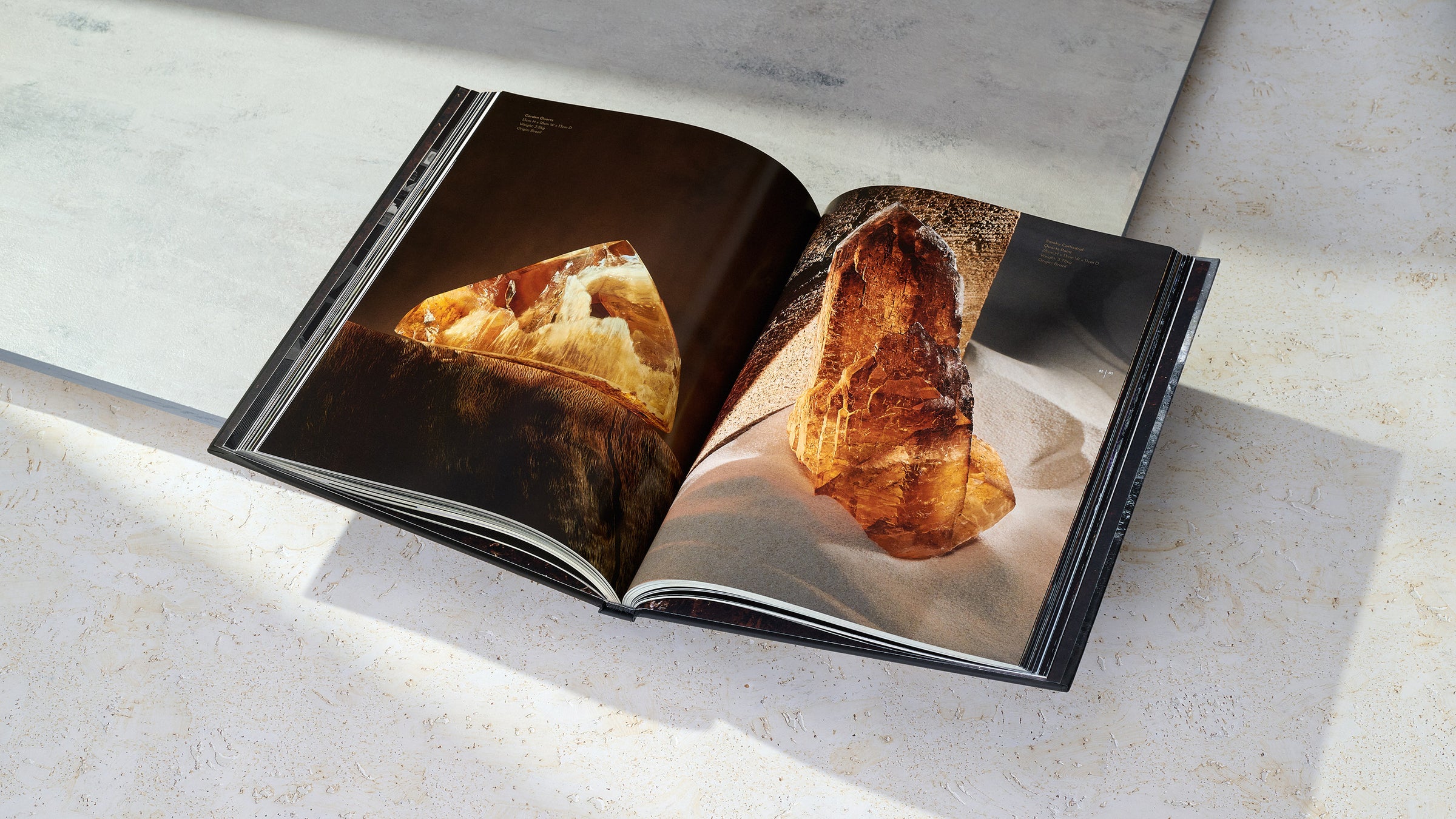 Smoky Cathedral Quartz from ARQUIVISTAS book. Book laying open to pages on marble background. 