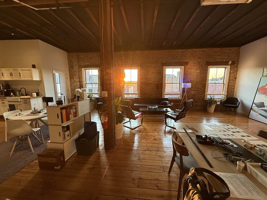 Golden-hour light fills the third-floor Art & Anthropology Press studio in Newburgh, NY — exposed brick, wood floors, and work tables